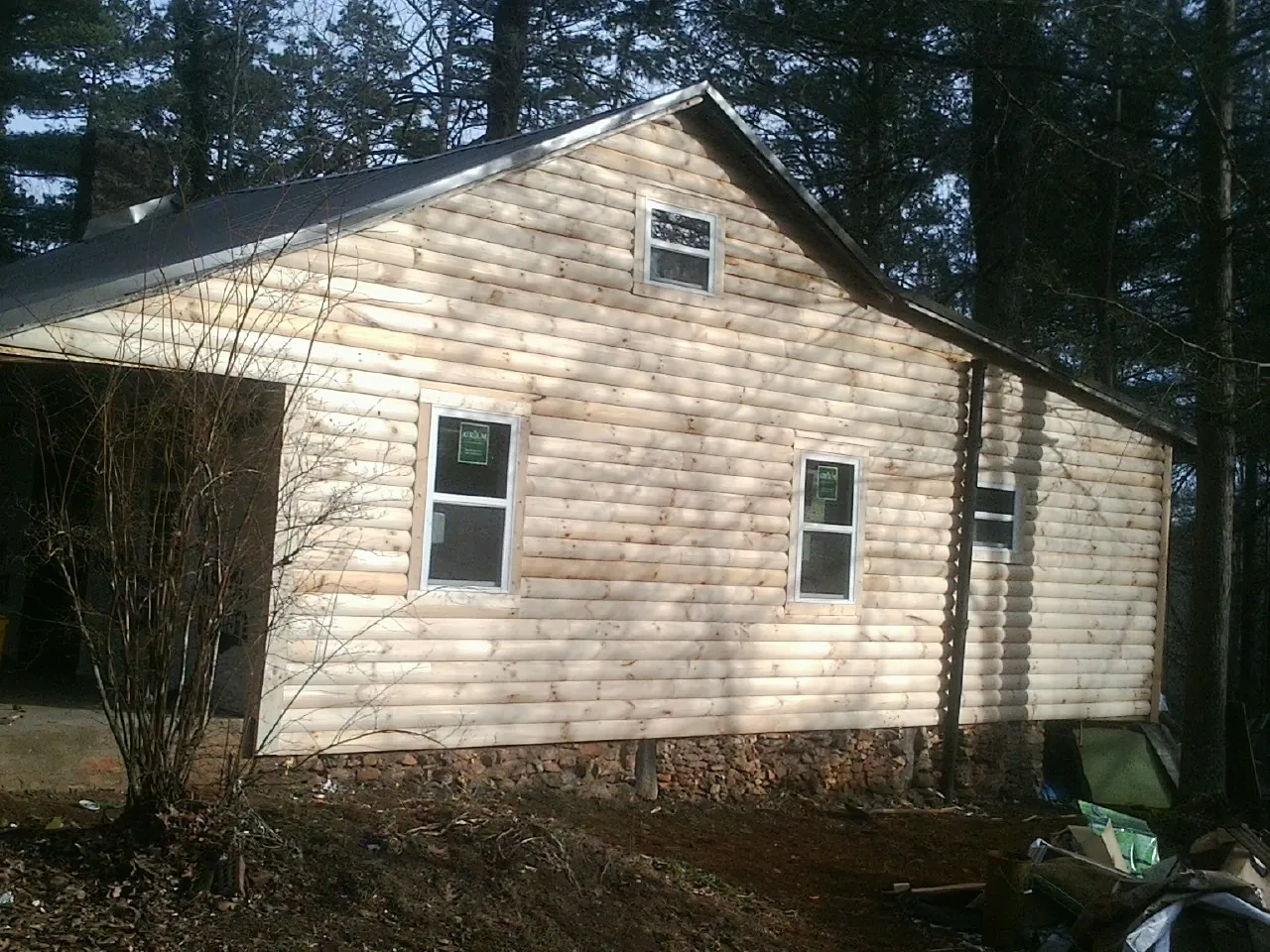 New log siding and dark metal roofing on a gable end in Collegeport