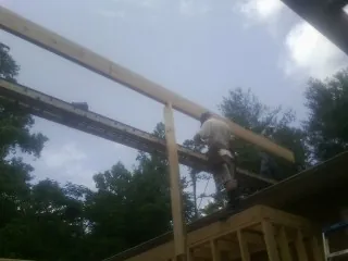 Carpenter setting a ridge beam over a new addition frame — Ice Dam Removal by Roofing Brothers in Collegeport
