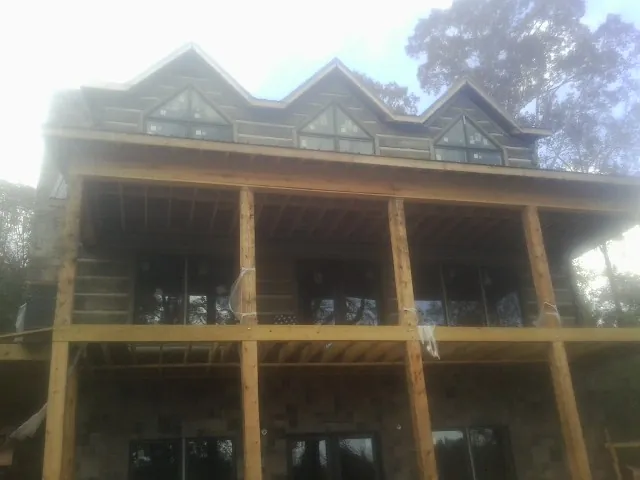 Dormers and porch framing on a large log home under construction — Roof Coating work by our crew in Collegeport