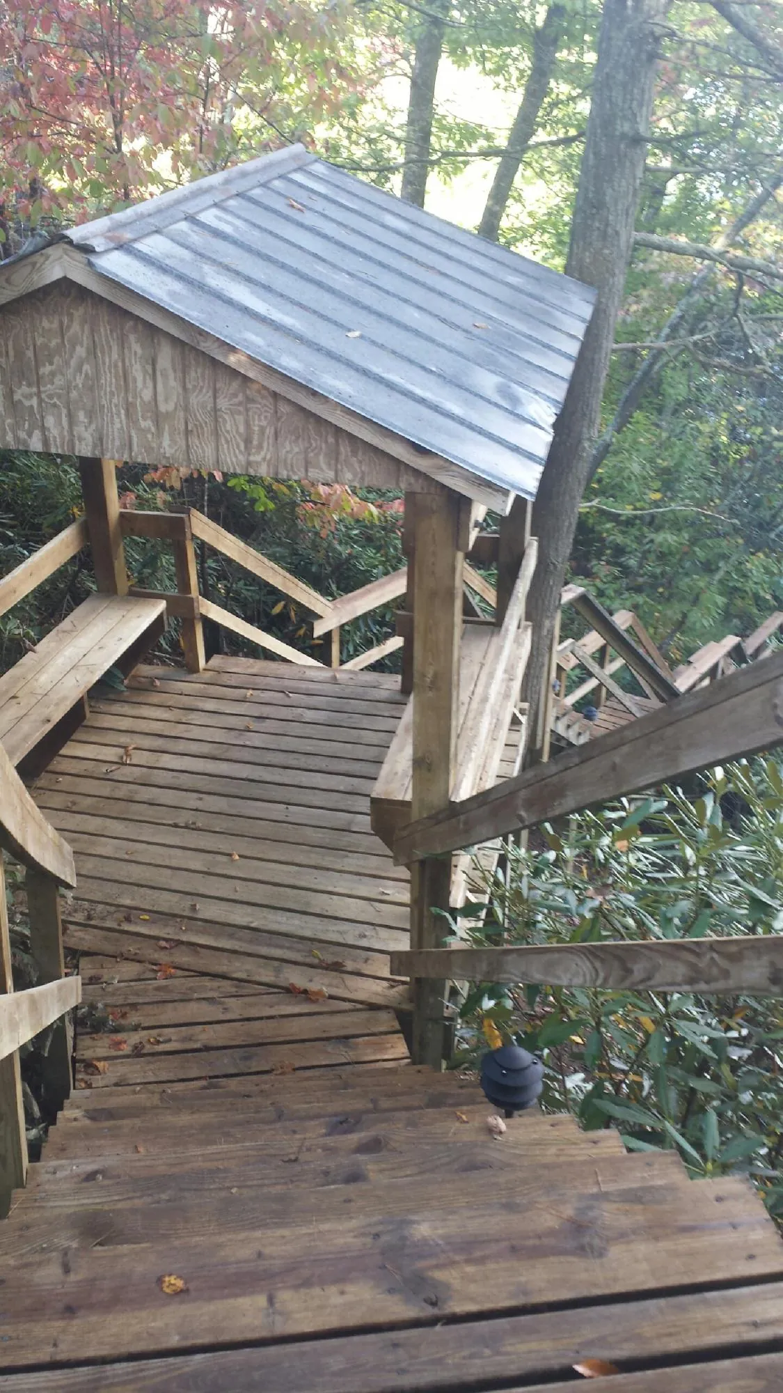 Metal roofed shelter over wooden steps on a wooded walkway — Skylight Repair & Installation work by our crew in Collegeport