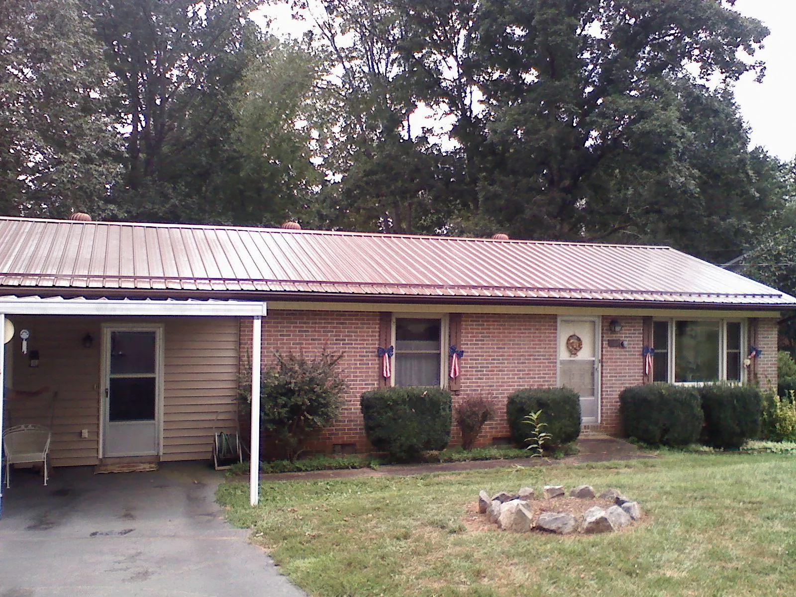 Bronze metal roof and carport on a brick ranch home — Roof Repair work by our crew in Collegeport