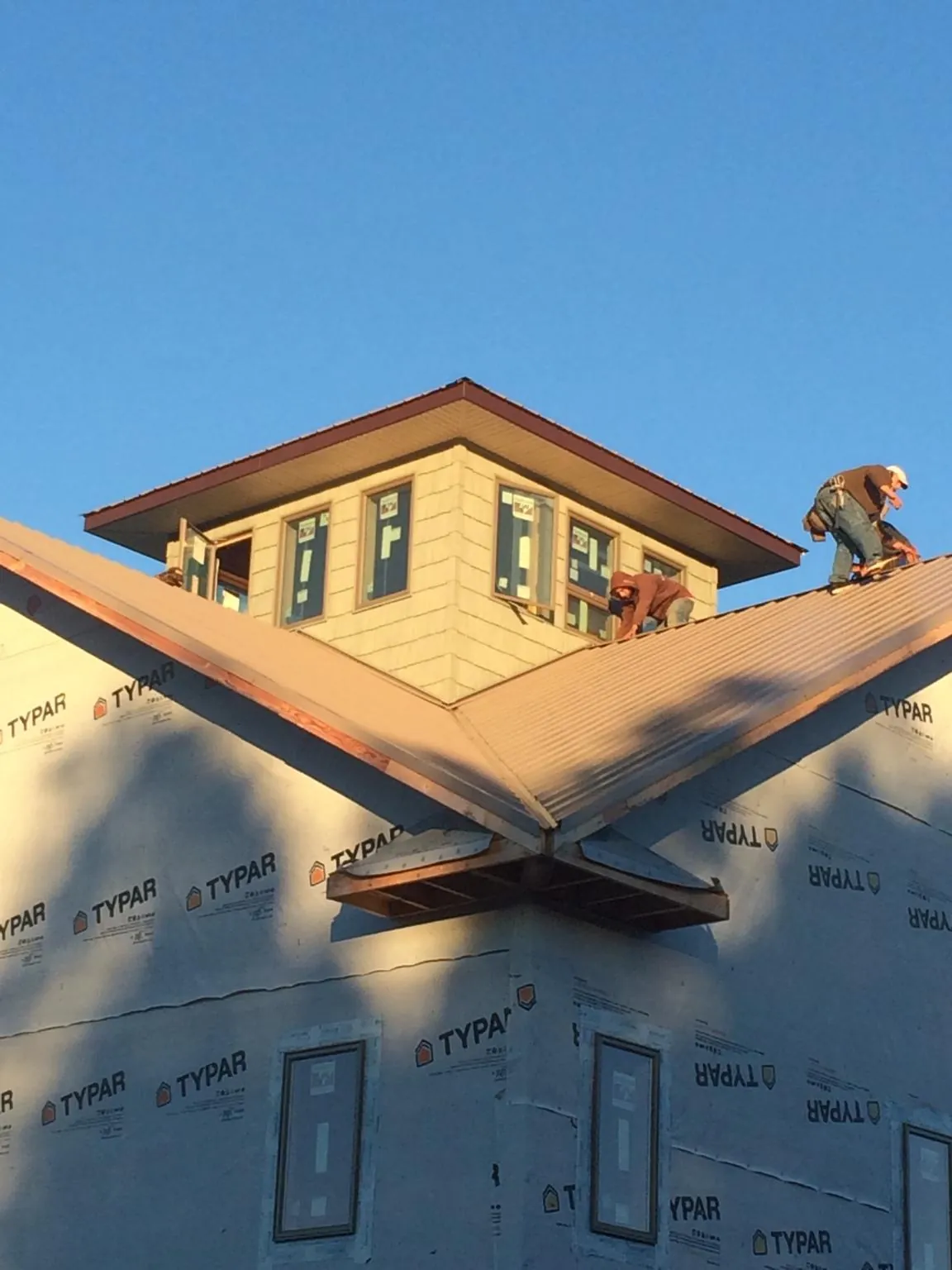 Roofers working around a rooftop cupola on a new metal roof at sunset — Roof Waterproofing in Collegeport by Roofing Brothers